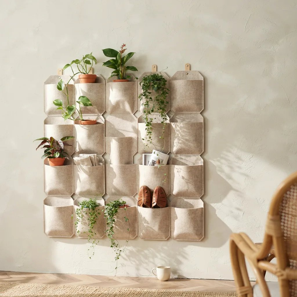 A modular felt pocket panel system mounted on a wall, partially planted with greenery