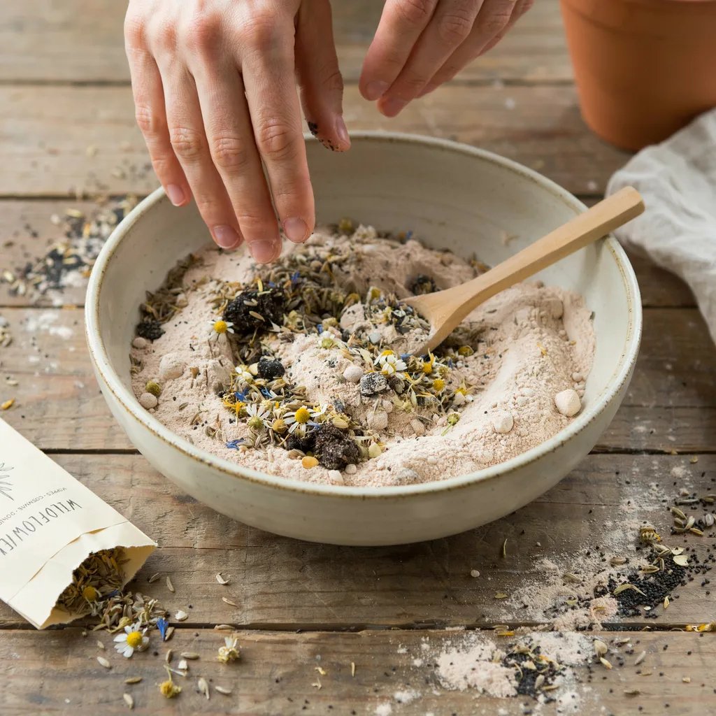 Mixing clay, compost, and seeds together to form seed bomb material